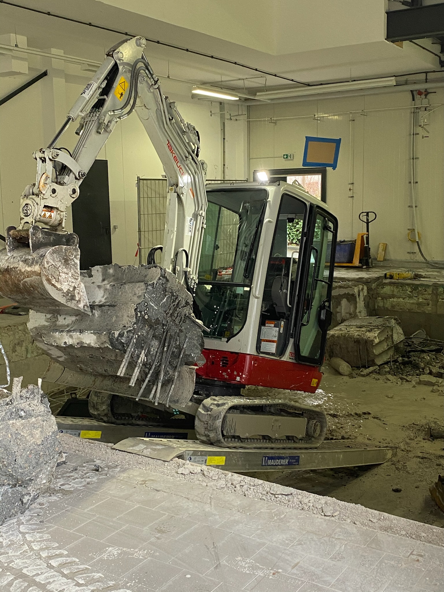 Minibagger bricht Betonboden und Fundamentteile in einer Halle in Backnang zurück