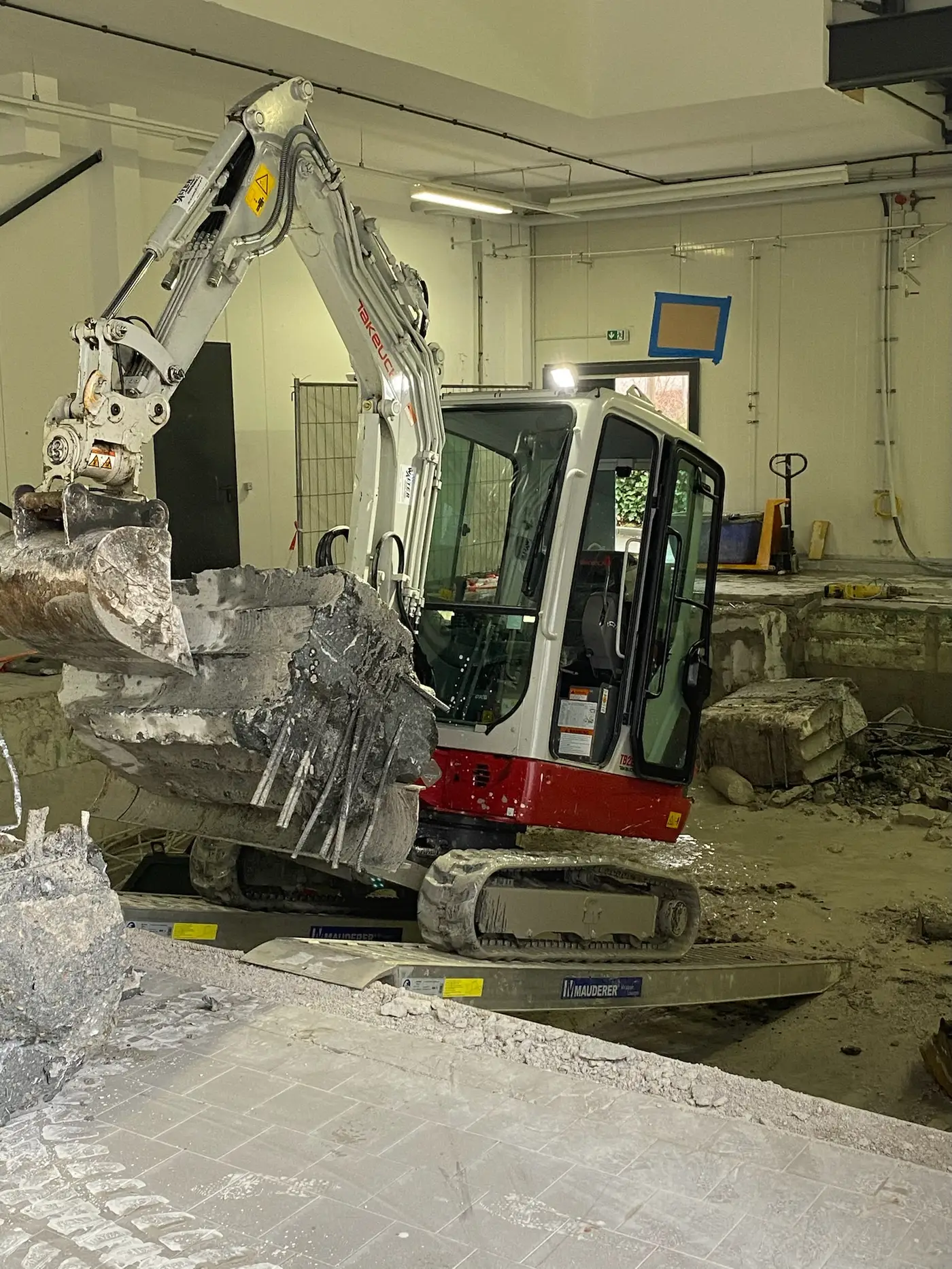Minibagger bricht Betonboden und Fundamentteile in einer Halle in Backnang zurück