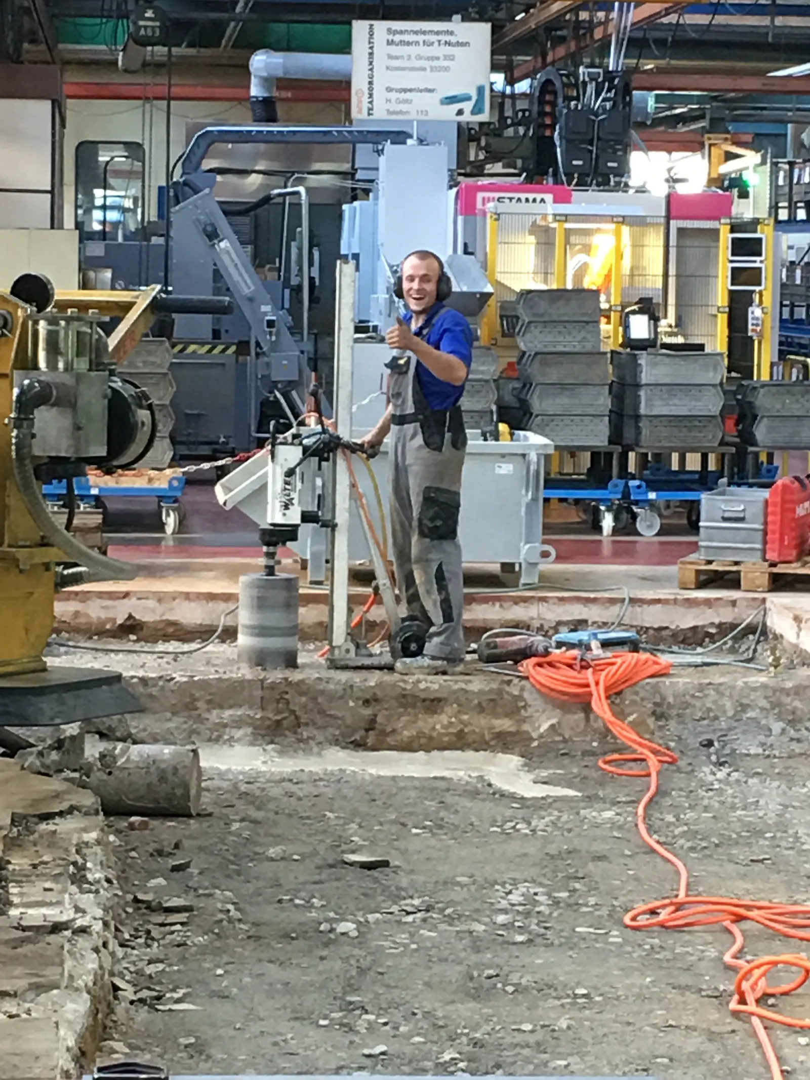 Mitarbeiter bedient ein Kernbohrgerät für eine Betonbohrung in einer Industriehalle in Backnang