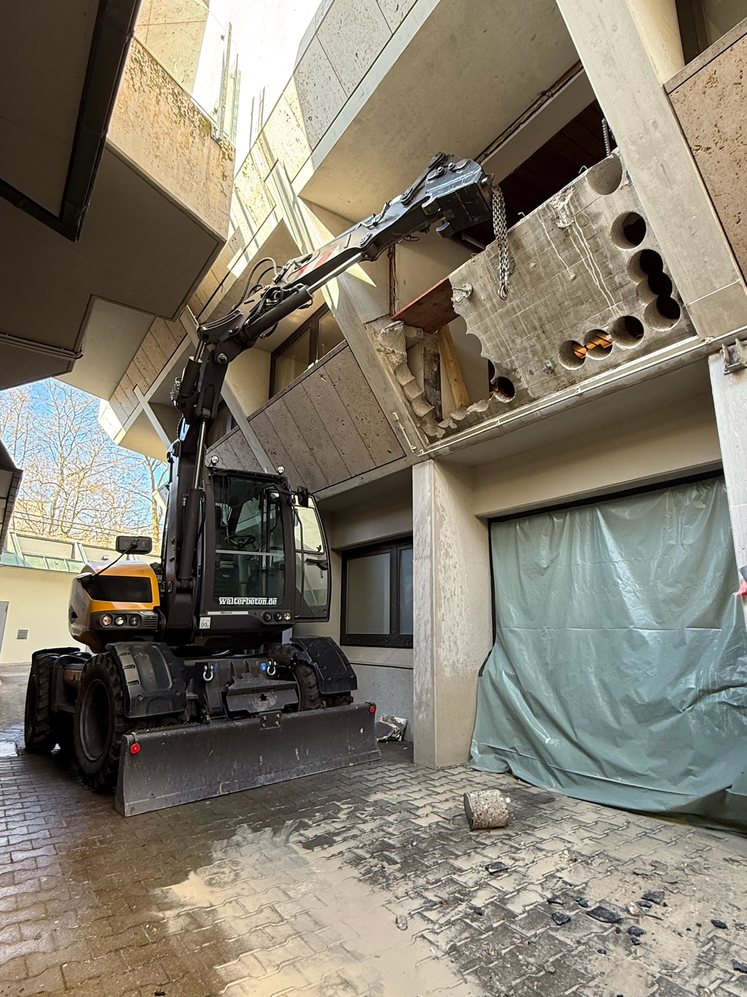 Mobilbagger hebt ausgesägtes Betonsegment aus einer Wandöffnung in Fellbach