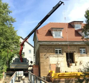 Autokran hebt Baumaterial an einem Wohnhaus bei Kranarbeiten in Sindelfingen