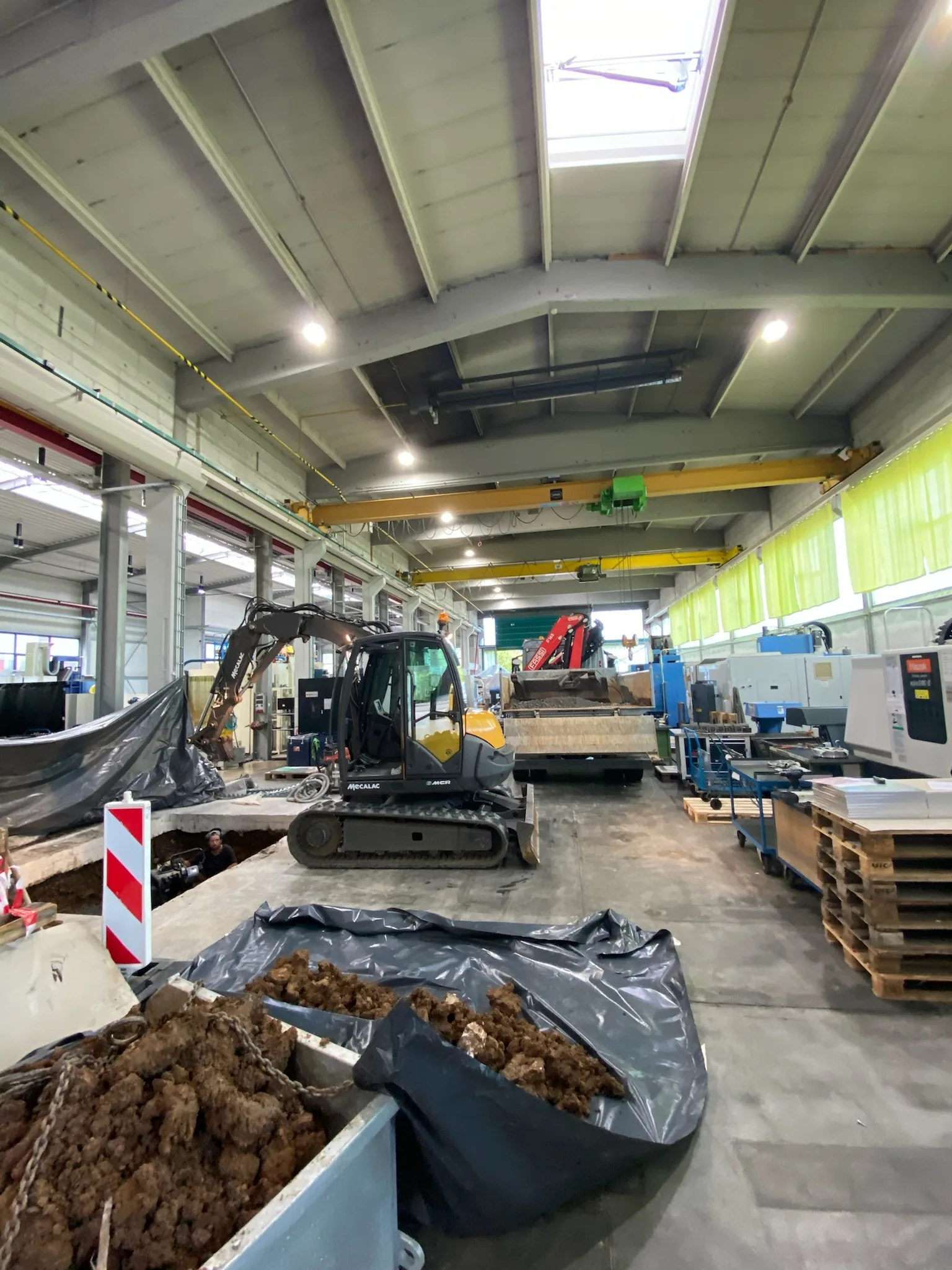 Minibagger bricht Industrieboden in einer Produktionshalle für Bodenplatten-Reparatur auf