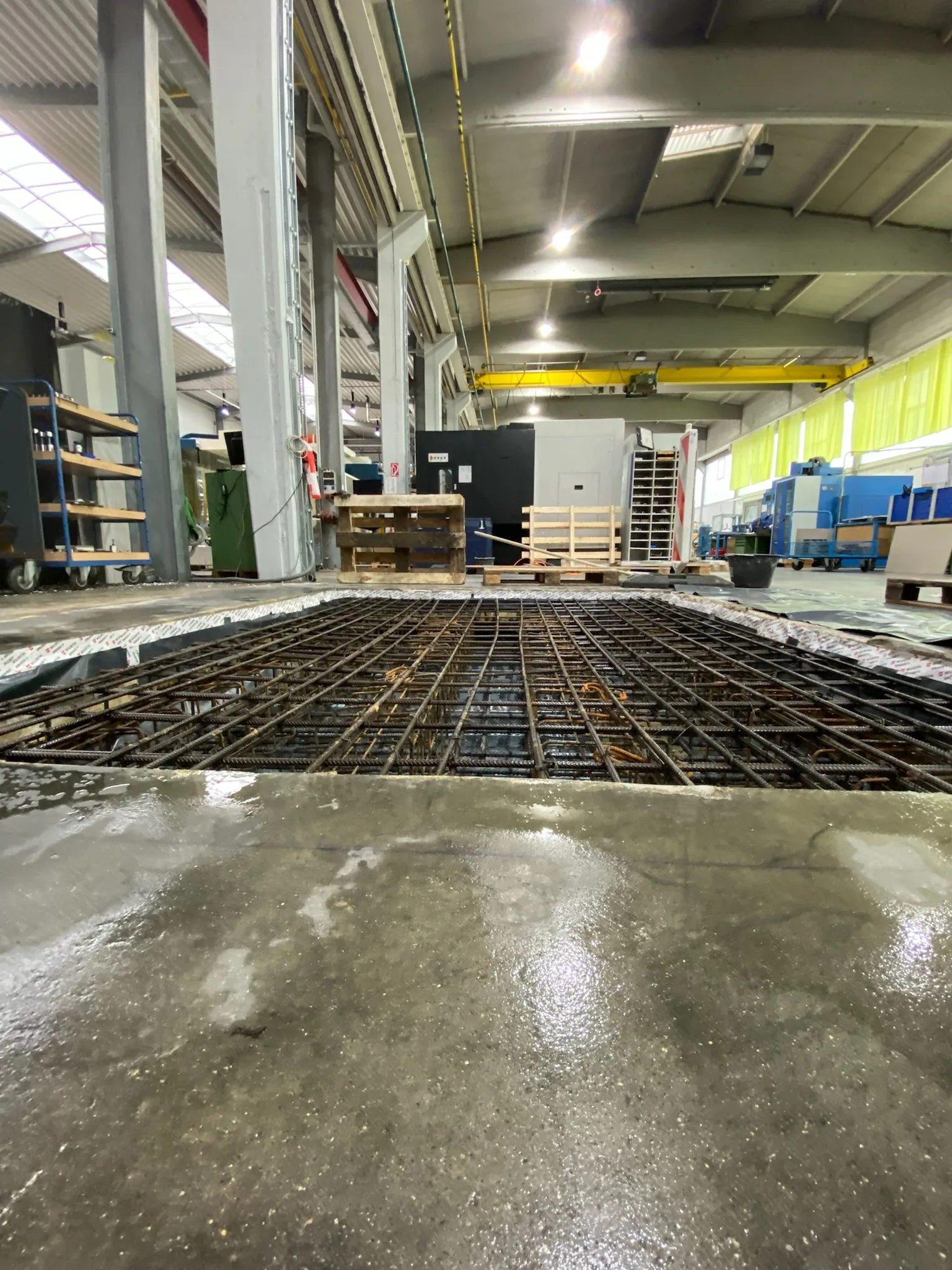 Neue Industriebodenplatte aus frischem Beton wird in einer Produktionshalle geglättet